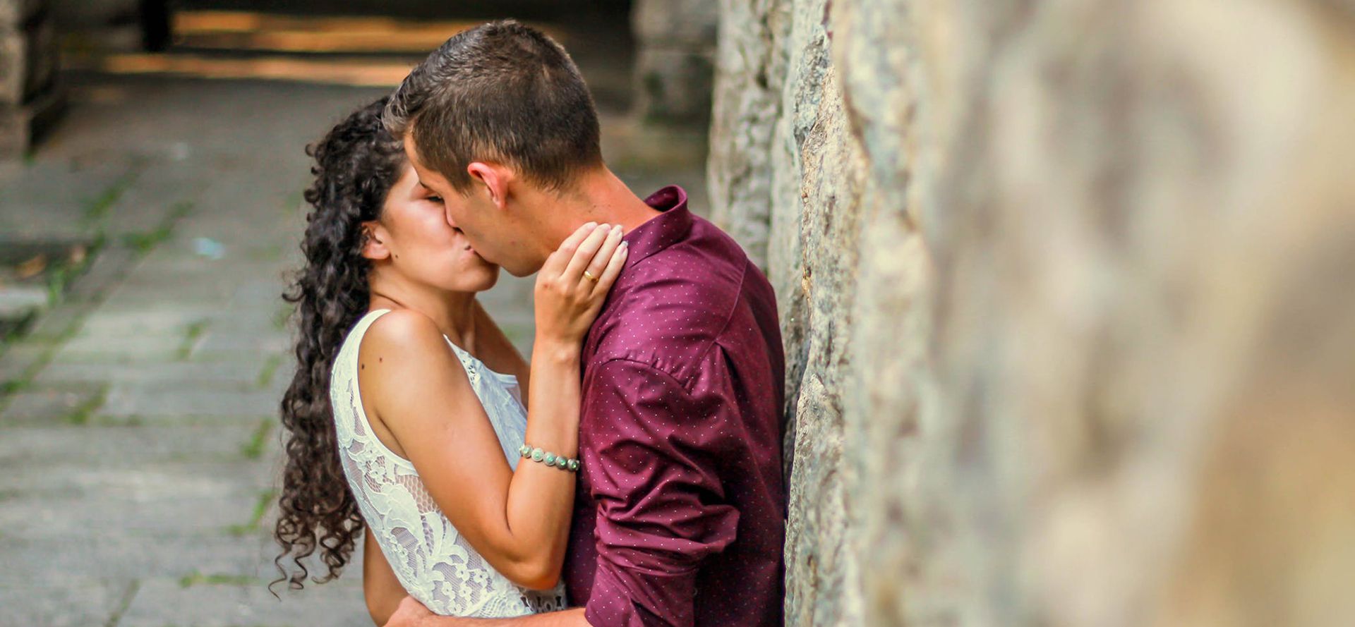 Adolescentes a beijarem-se perto da parede.